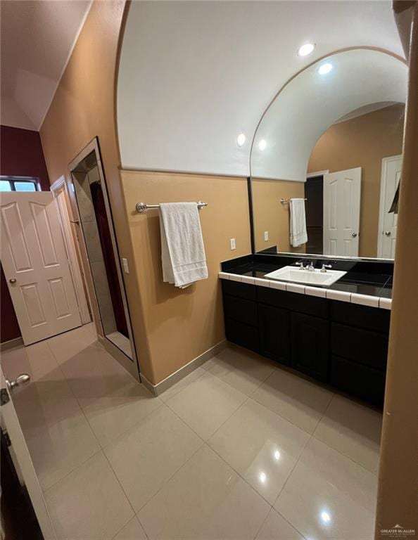 bathroom featuring tile patterned flooring, vanity, and lofted ceiling