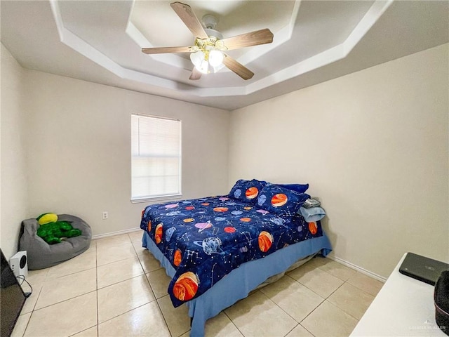 tiled bedroom with ceiling fan and a tray ceiling