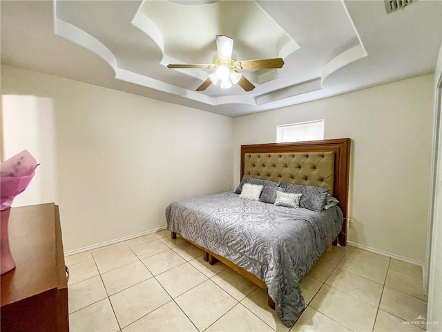 tiled bedroom with a raised ceiling and ceiling fan