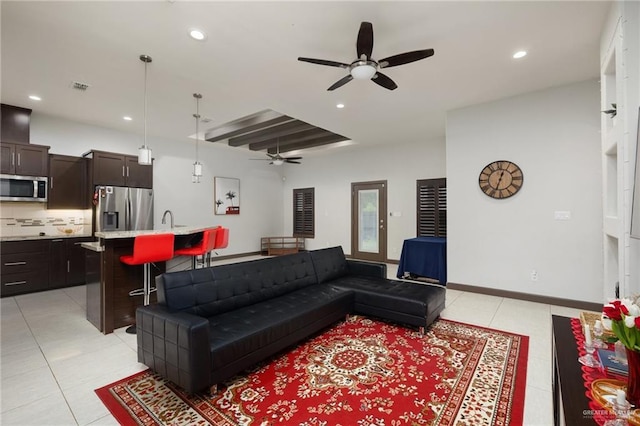 living room featuring light tile patterned flooring, ceiling fan, and beamed ceiling