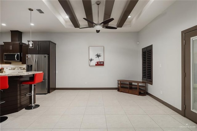 kitchen with appliances with stainless steel finishes, beamed ceiling, ceiling fan, pendant lighting, and light stone counters