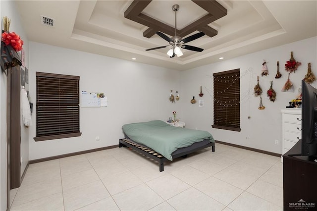 tiled bedroom with ceiling fan and a tray ceiling