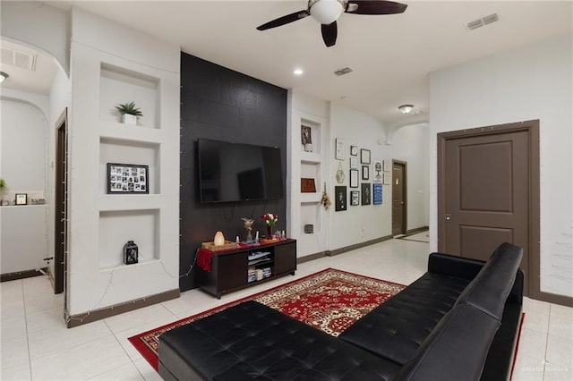 living room featuring built in shelves, ceiling fan, and light tile patterned floors