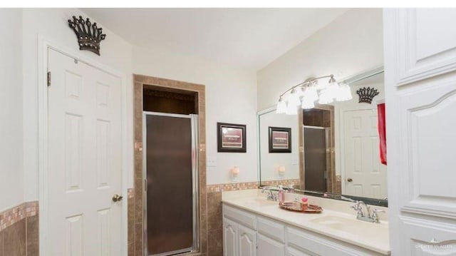 bathroom featuring a shower with door, vanity, and tile walls