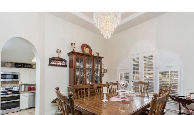 dining space featuring a towering ceiling and a notable chandelier