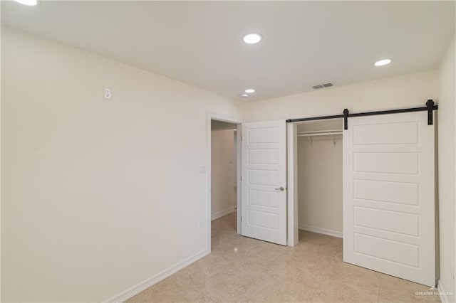 unfurnished bedroom featuring a barn door and a closet