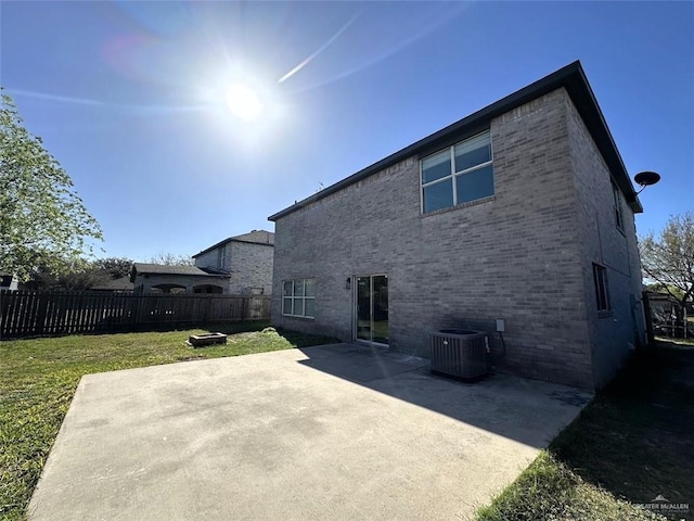 back of property featuring brick siding, cooling unit, a patio area, and a yard