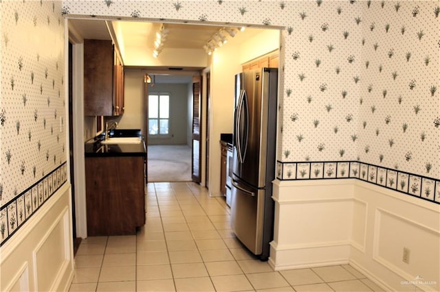 kitchen with light tile patterned floors, sink, stainless steel refrigerator, track lighting, and decorative light fixtures