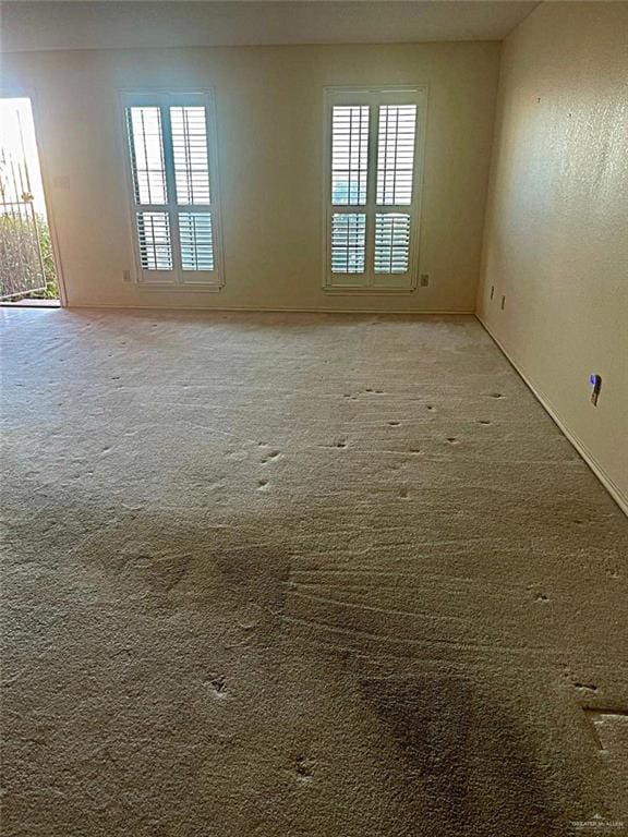 unfurnished room featuring a healthy amount of sunlight and carpet