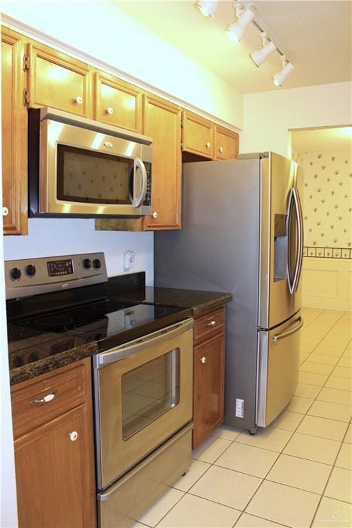 kitchen featuring stainless steel appliances, dark stone countertops, and light tile patterned floors