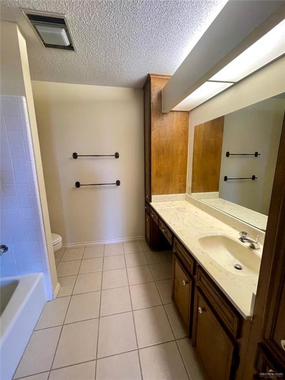 bathroom featuring tile patterned flooring, vanity, toilet, and a textured ceiling