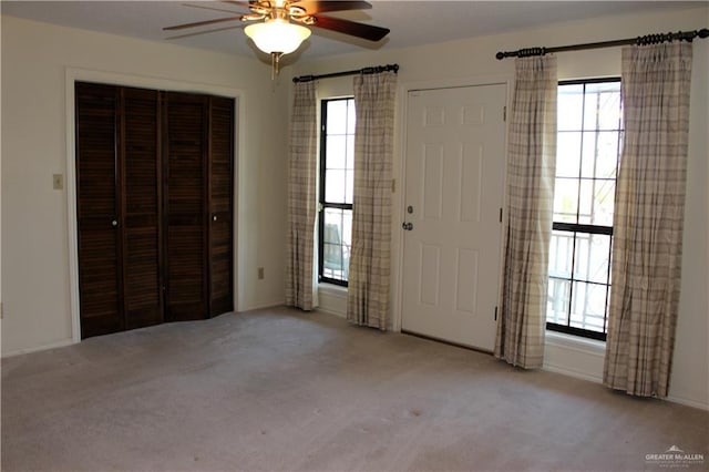 carpeted foyer entrance featuring plenty of natural light and ceiling fan