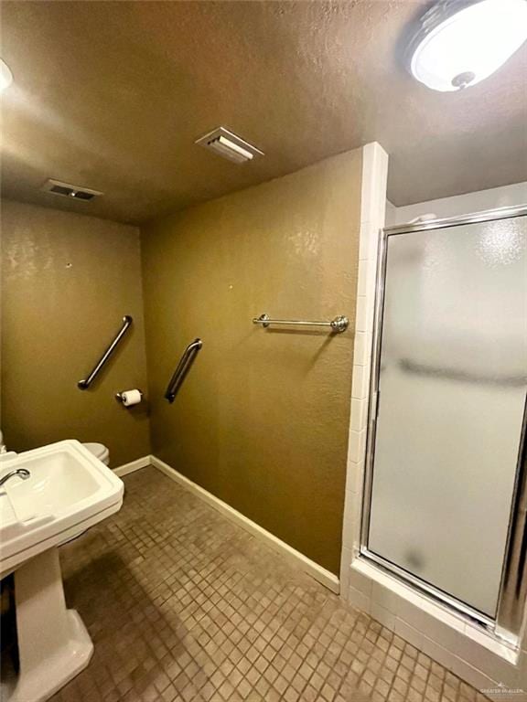 bathroom featuring an enclosed shower and a textured ceiling