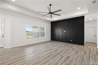 unfurnished bedroom with a raised ceiling and light wood-type flooring