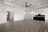 living room featuring a tray ceiling, ceiling fan, and dark wood-type flooring