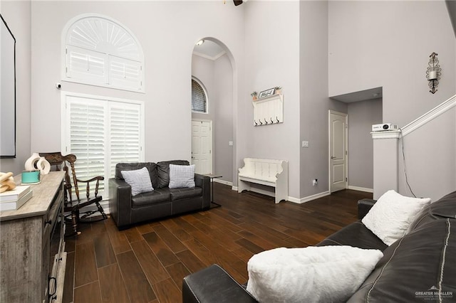 living room with baseboards, arched walkways, a high ceiling, and wood finished floors