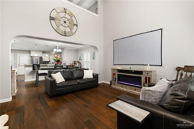 living area with arched walkways, a high ceiling, and dark wood-style flooring