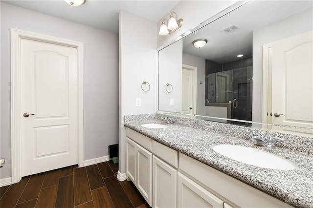 full bath featuring double vanity, a stall shower, wood finish floors, and a sink