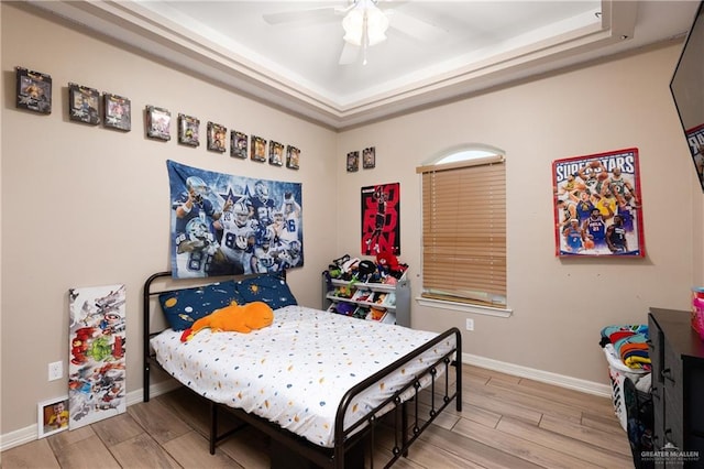 bedroom with baseboards, a tray ceiling, and wood tiled floor