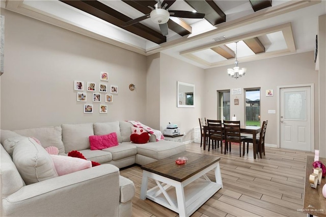 living area featuring a tray ceiling, light wood-style floors, beamed ceiling, baseboards, and ceiling fan with notable chandelier