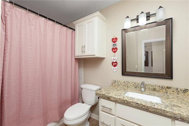 bathroom featuring toilet, baseboards, and vanity