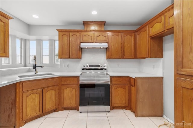 2407 Flores Dr, Mission, TX 78574 - kitchen with stainless steel electric range oven, under cabinet range hood, a sink, brown cabinetry, and recessed lighting