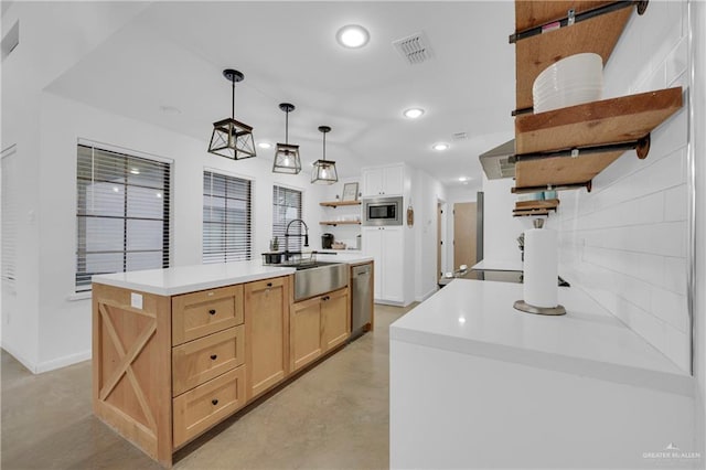 kitchen featuring sink, light brown cabinets, hanging light fixtures, stainless steel appliances, and a kitchen island with sink