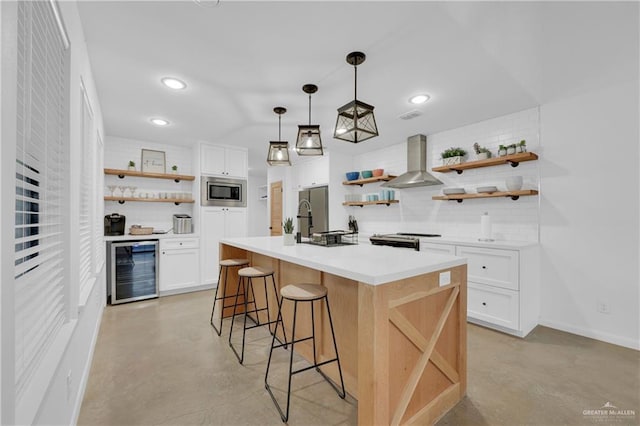 kitchen featuring white cabinets, tasteful backsplash, a kitchen island with sink, and wall chimney range hood