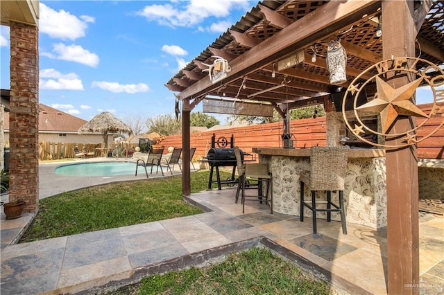 view of patio / terrace featuring a fenced in pool, an outdoor bar, and grilling area