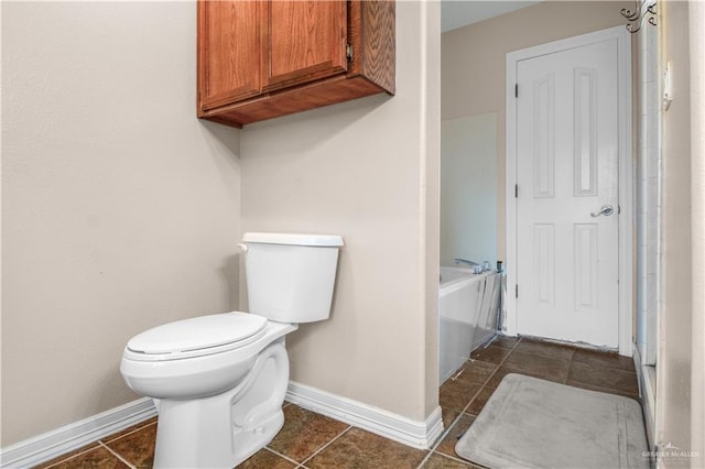 bathroom with tile patterned floors, a tub to relax in, and toilet