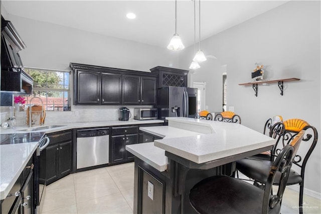 kitchen with light tile patterned flooring, a breakfast bar, hanging light fixtures, appliances with stainless steel finishes, and a kitchen island