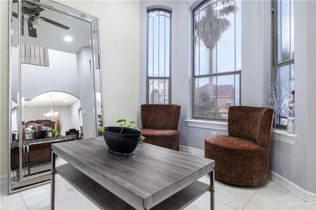 sitting room featuring ceiling fan with notable chandelier and light tile patterned flooring