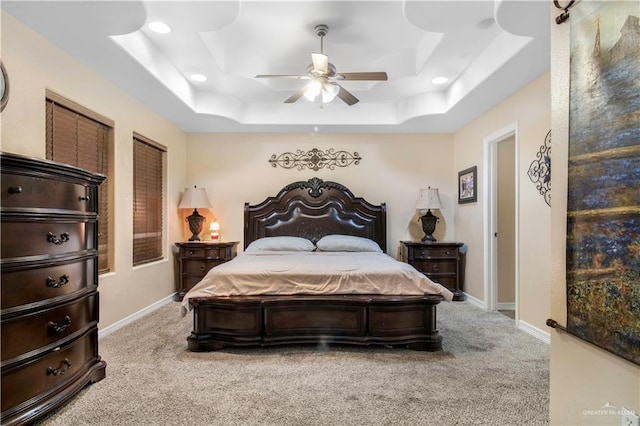 bedroom featuring ceiling fan, a tray ceiling, and carpet