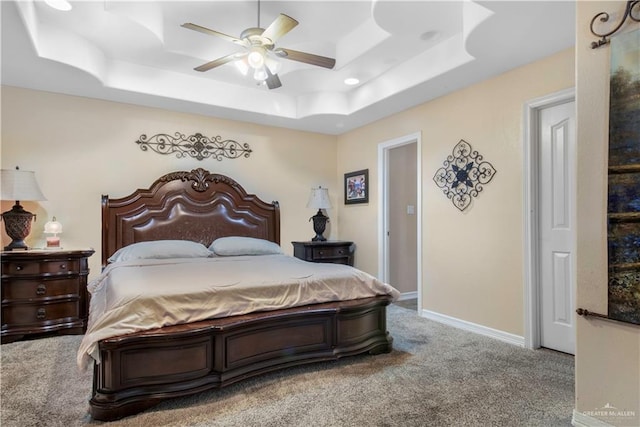 carpeted bedroom with a tray ceiling and ceiling fan