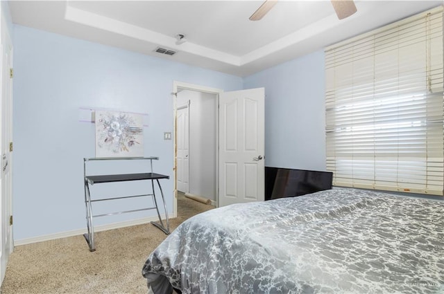 bedroom with light carpet, a raised ceiling, and ceiling fan