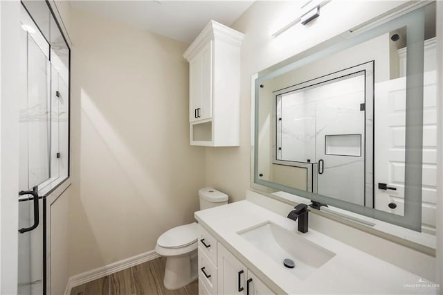 bathroom featuring hardwood / wood-style floors, vanity, an enclosed shower, and toilet