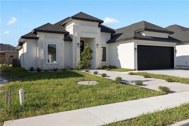 prairie-style home featuring a garage, a front lawn, and cooling unit