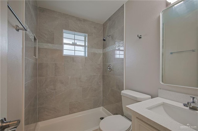 bathroom with vanity, a tile shower, and toilet