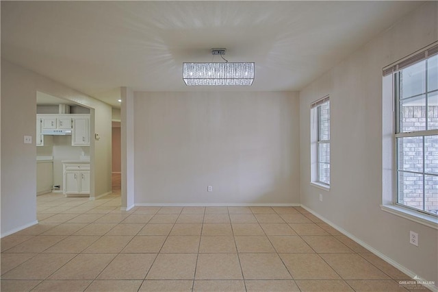 empty room featuring light tile patterned floors, a chandelier, and a healthy amount of sunlight