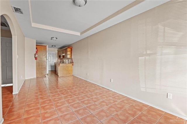 unfurnished living room with a tray ceiling and light tile patterned flooring