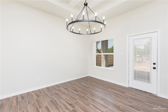 unfurnished dining area featuring an inviting chandelier, baseboards, wood finished floors, and beamed ceiling
