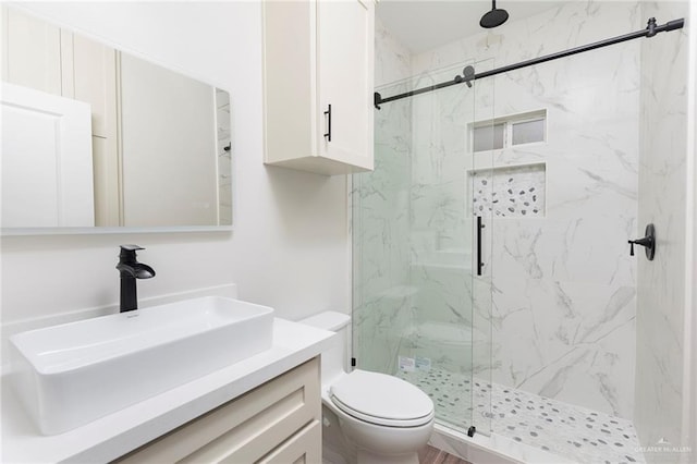 bathroom featuring a marble finish shower, vanity, and toilet