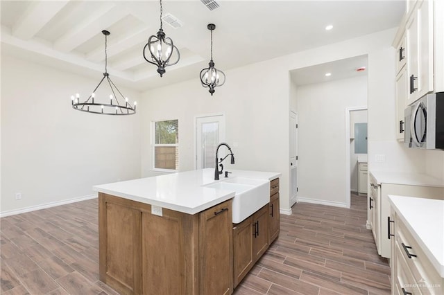 kitchen with wood finished floors, recessed lighting, stainless steel microwave, a chandelier, and a sink
