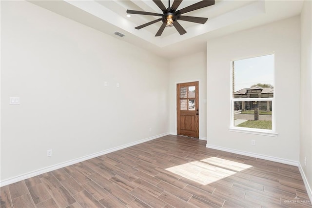 unfurnished room featuring visible vents, baseboards, wood finished floors, and a tray ceiling