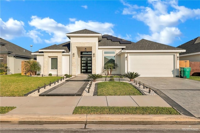 prairie-style house with a front lawn, solar panels, french doors, decorative driveway, and a garage