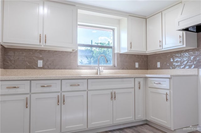 kitchen featuring custom range hood, white cabinetry, sink, and tasteful backsplash