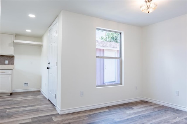 spare room featuring an inviting chandelier and light hardwood / wood-style flooring