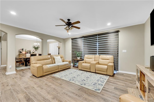 living room with crown molding, ceiling fan with notable chandelier, and light hardwood / wood-style floors