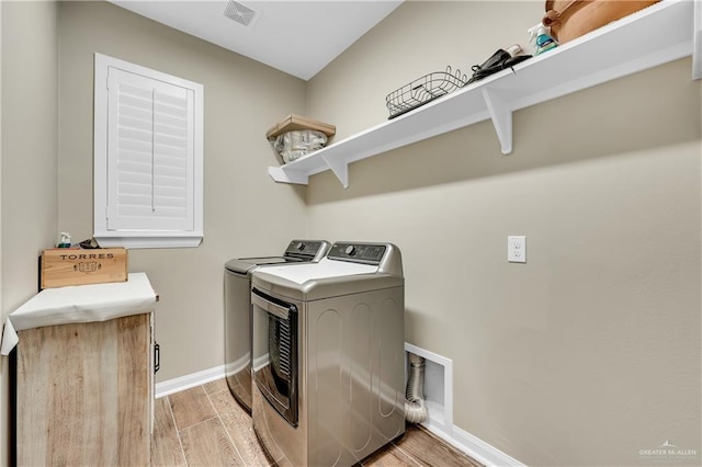 laundry room featuring washer and clothes dryer and light hardwood / wood-style flooring