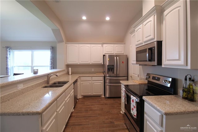 kitchen with white cabinets, sink, vaulted ceiling, light stone countertops, and appliances with stainless steel finishes